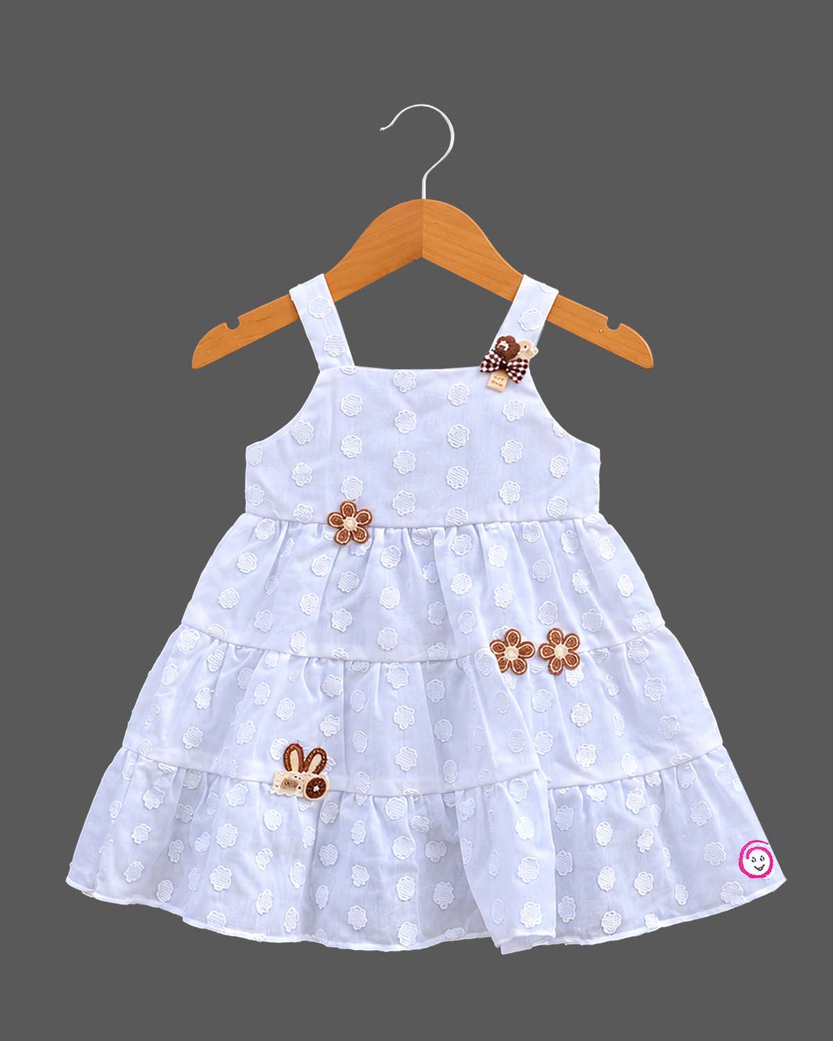 Sleeveless tiered frock with decorative appliques and casual frock details.