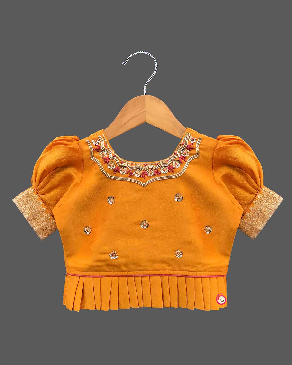Three-piece ethnic traditional outfit for girls comprising an embroidered top with puff sleeves, a pleated zari skirt, and a light dupatta.