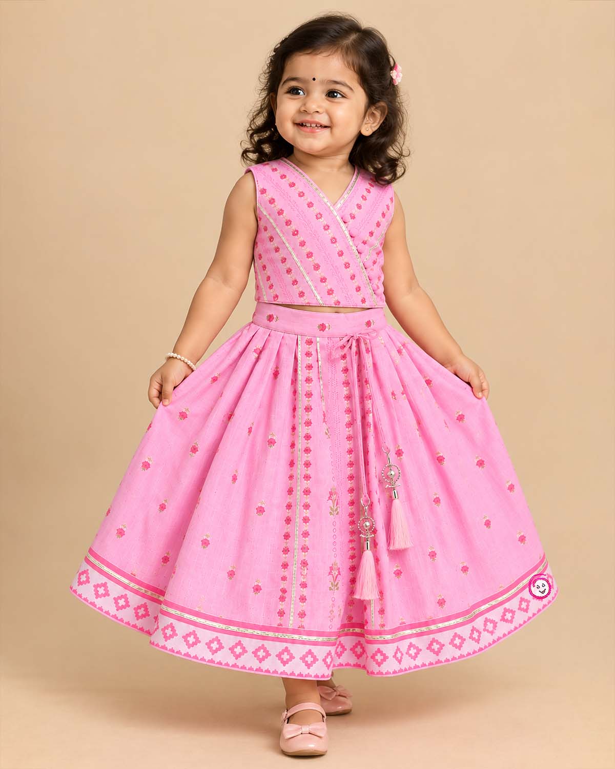 Girls angrakha lehenga choli set with floral prints, potli button details, and drawstring tassels.