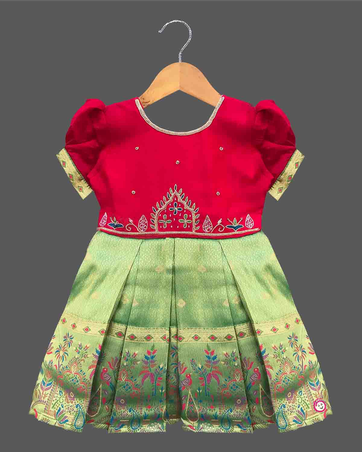 Detailed shot of a baby girl ethnic silk frock featuring traditional floral embroidery and puff sleeves.