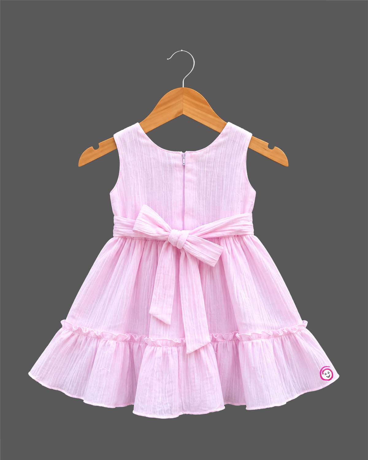 Sleeveless textured crinkle cotton frock with waist bow accent, lace trim, and tiered ruffle hemline for girls.