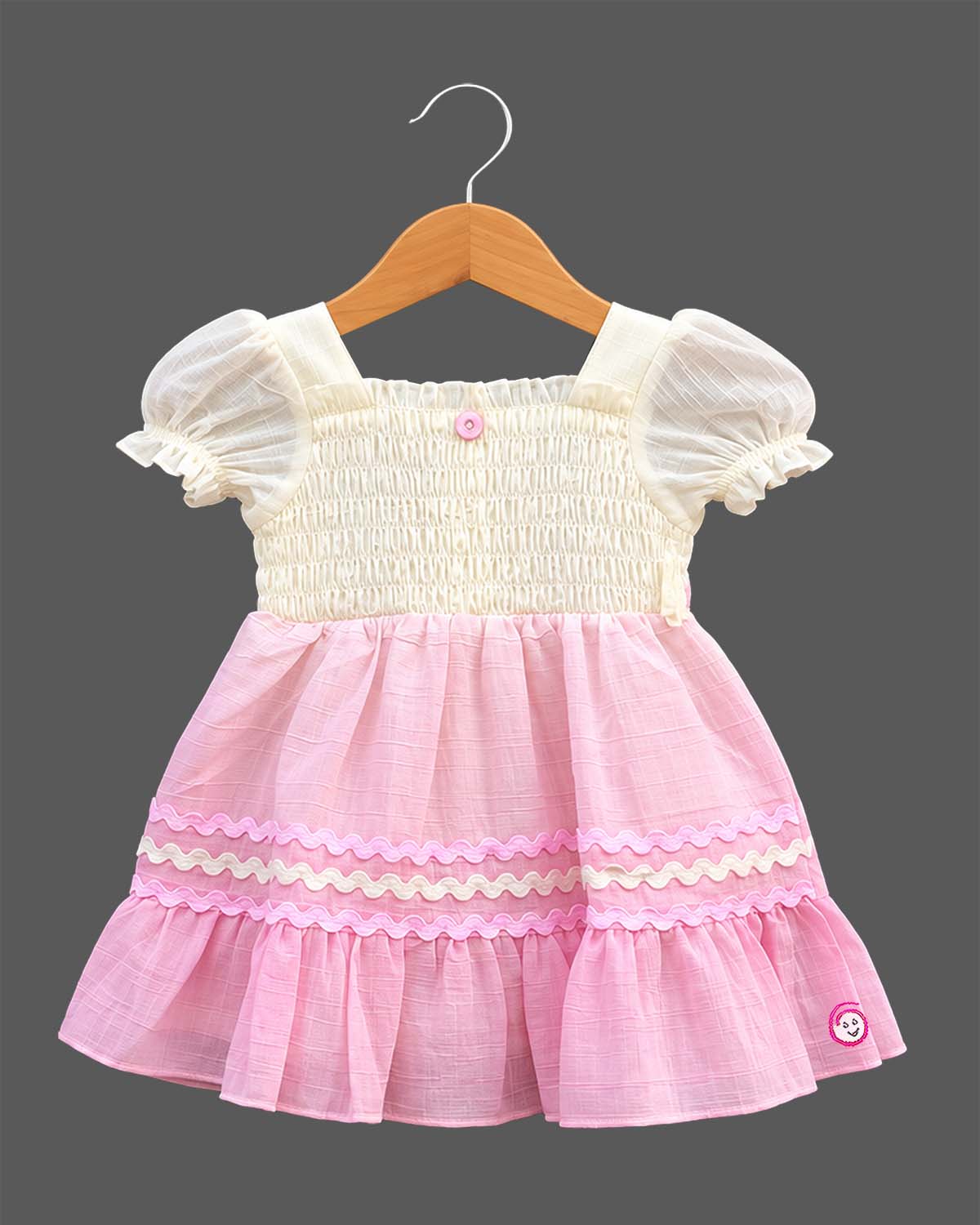 Toddler girls smocked bodice frock with puff sleeves, square neckline, and ric-rac trimmed ruffle hem.