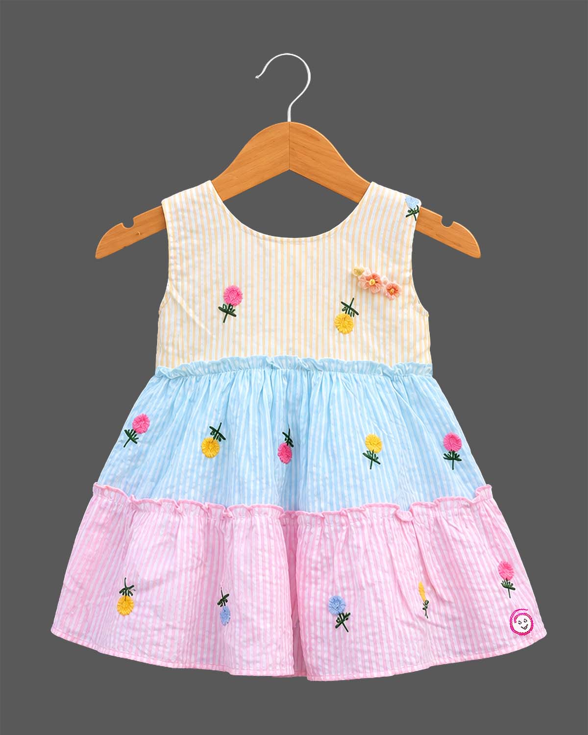 Sleeveless striped tiered frock with floral embroidered motifs and decorative shoulder applique accents.