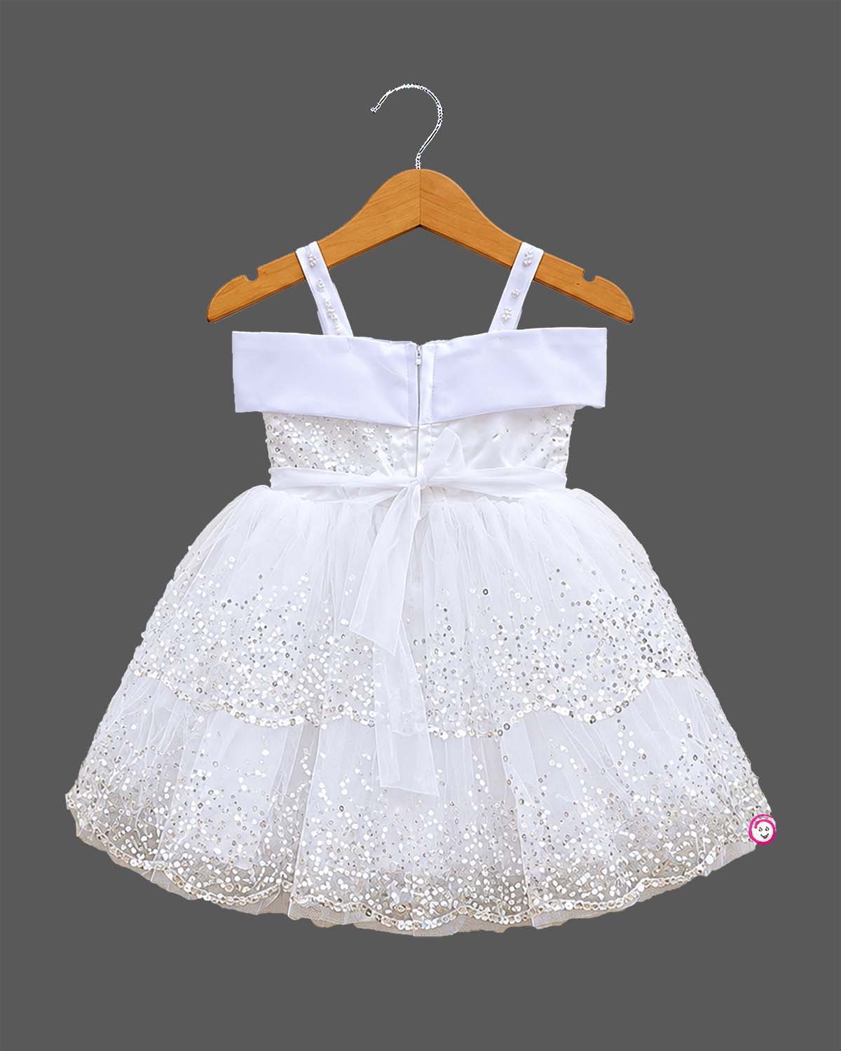 Girls sequined net frock with pearl embellished straps, satin bow with flower, and tiered scalloped flare skirt.