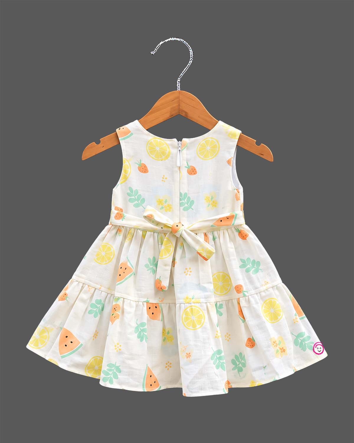 Sleeveless fruit print tiered cotton frock for girls featuring floral waist appliqué and flared A-line silhouette.