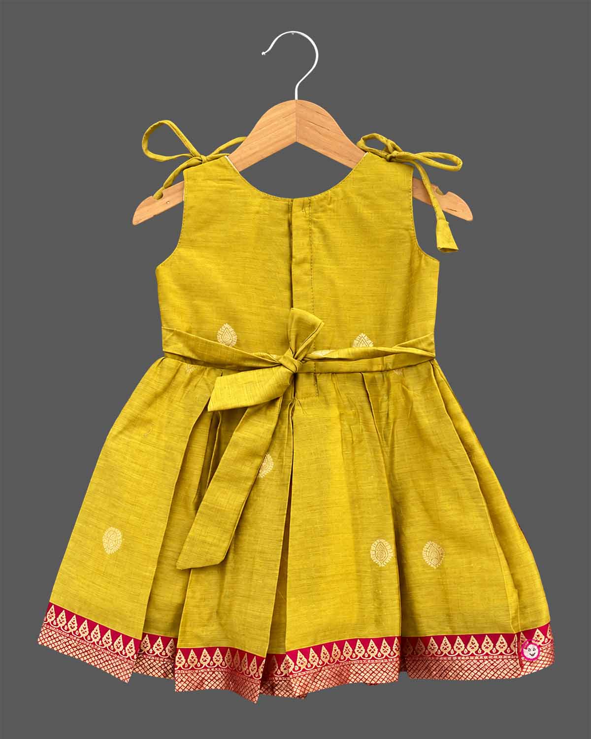 Toddler ethnic frock with jacquard woven borders, shoulder ties, and box pleats.