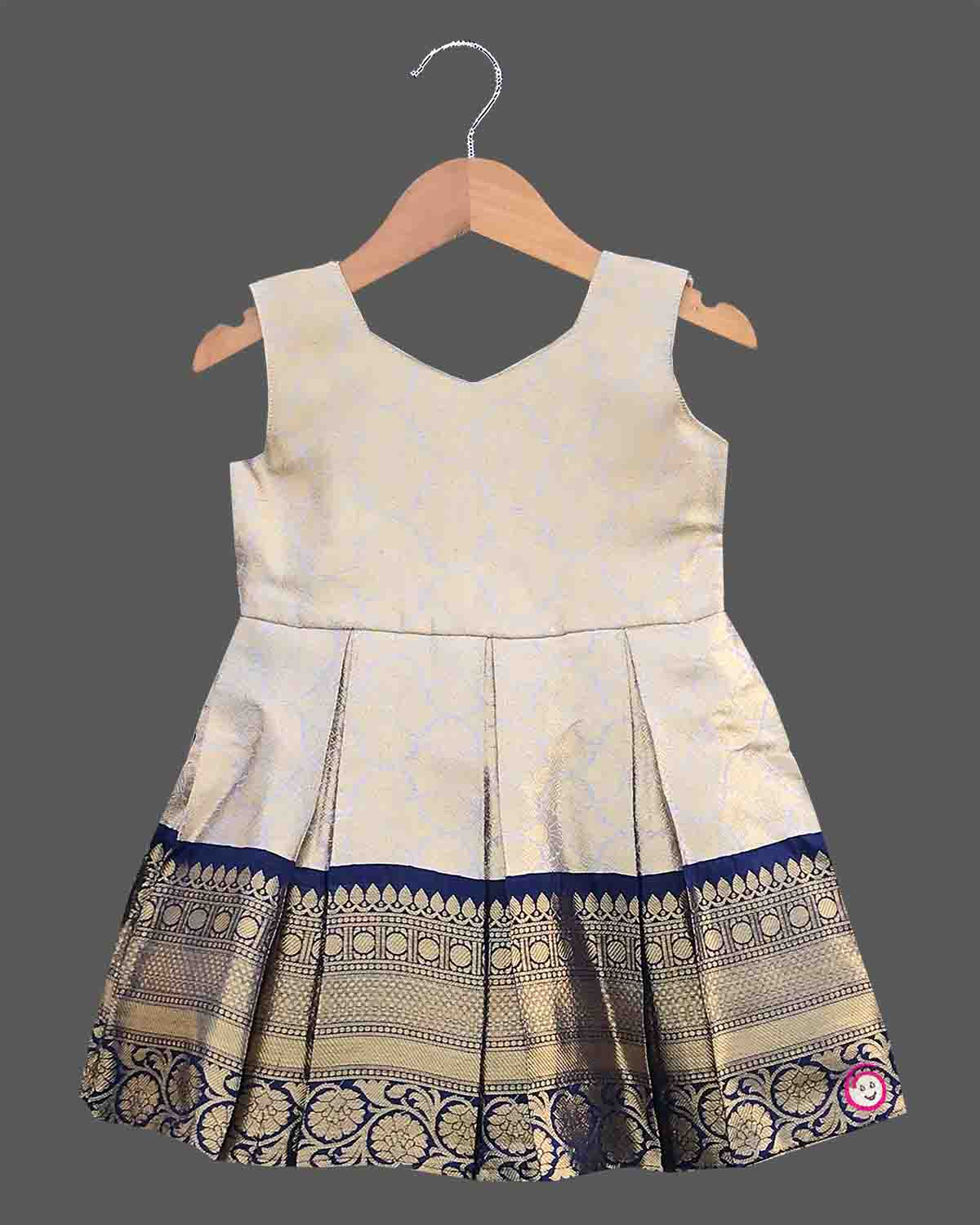 Infant silk cotton frock in cream and navy blue with attached jacket style design, front tie-up tassels, and a traditional heavy gold zari border