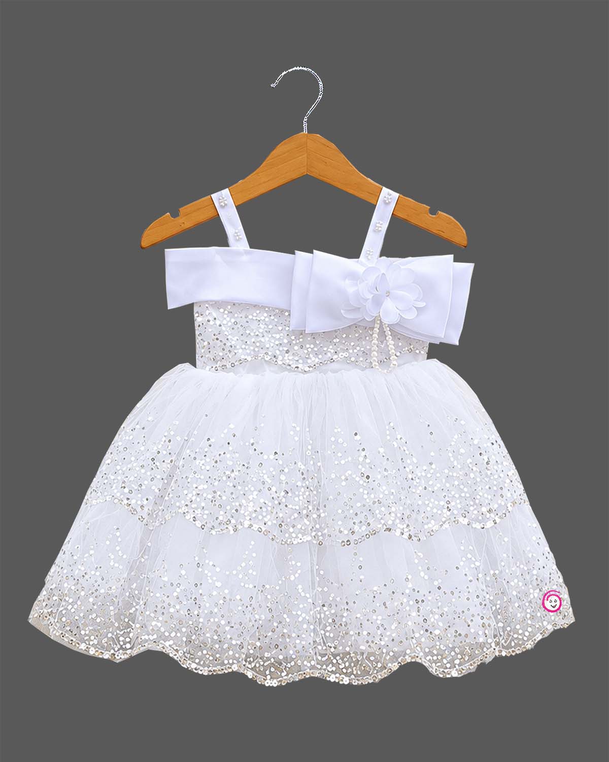 Girls sequined net frock with pearl embellished straps, satin bow with flower, and tiered scalloped flare skirt.