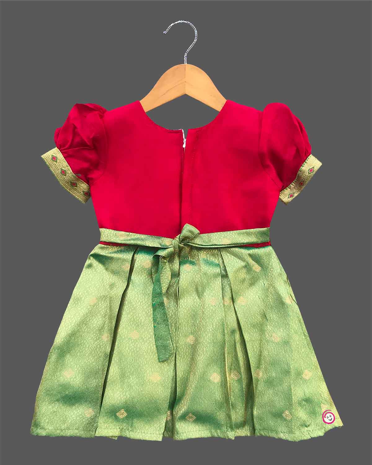 Detailed shot of a baby girl ethnic silk frock featuring traditional floral embroidery and puff sleeves.