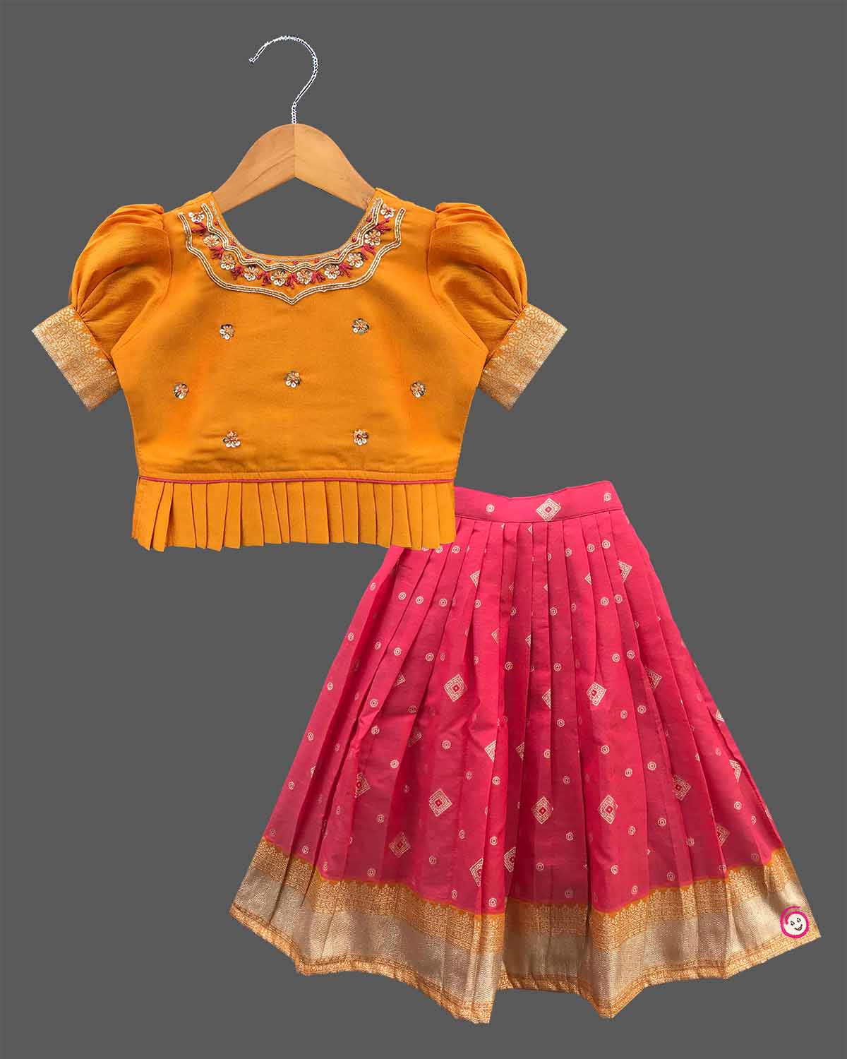 Three-piece ethnic traditional outfit for girls comprising an embroidered top with puff sleeves, a pleated zari skirt, and a light dupatta.