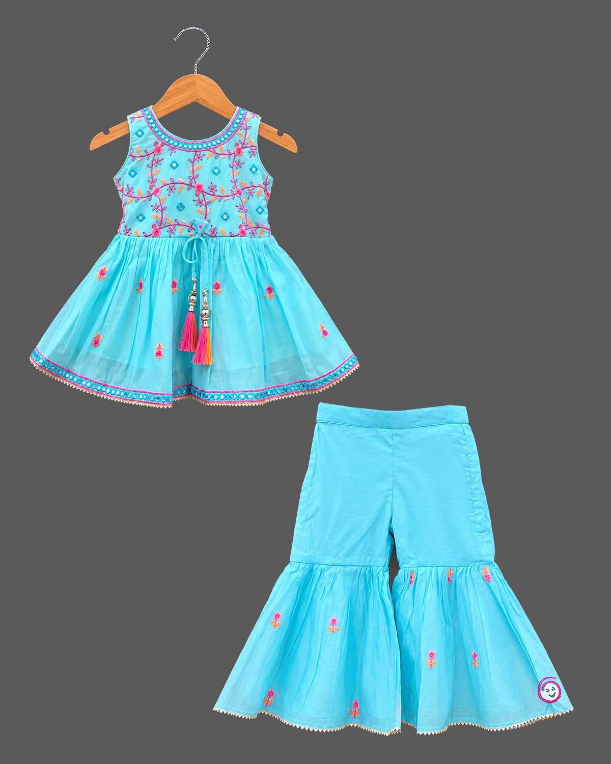 Girls sleeveless embroidered peplum kurti paired with tiered flared sharara pants featuring tassel ties.