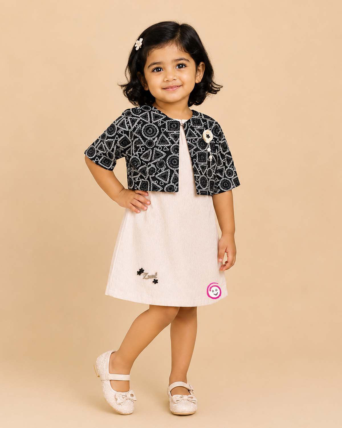Black and white geometric jacket over a cream baby girl cotton midi dress for family dinners, evening outings, and smart casual wear