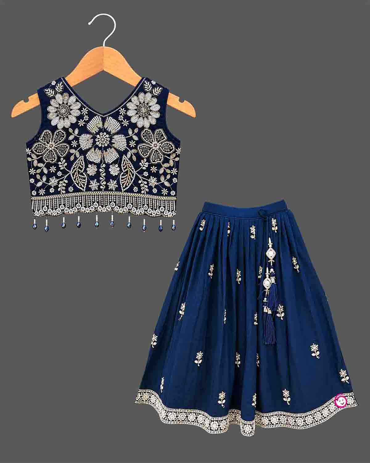 Girls sleeveless embroidered choli lehenga set with beaded fringe hem, tassel drawstring, and pleated flared skirt.
