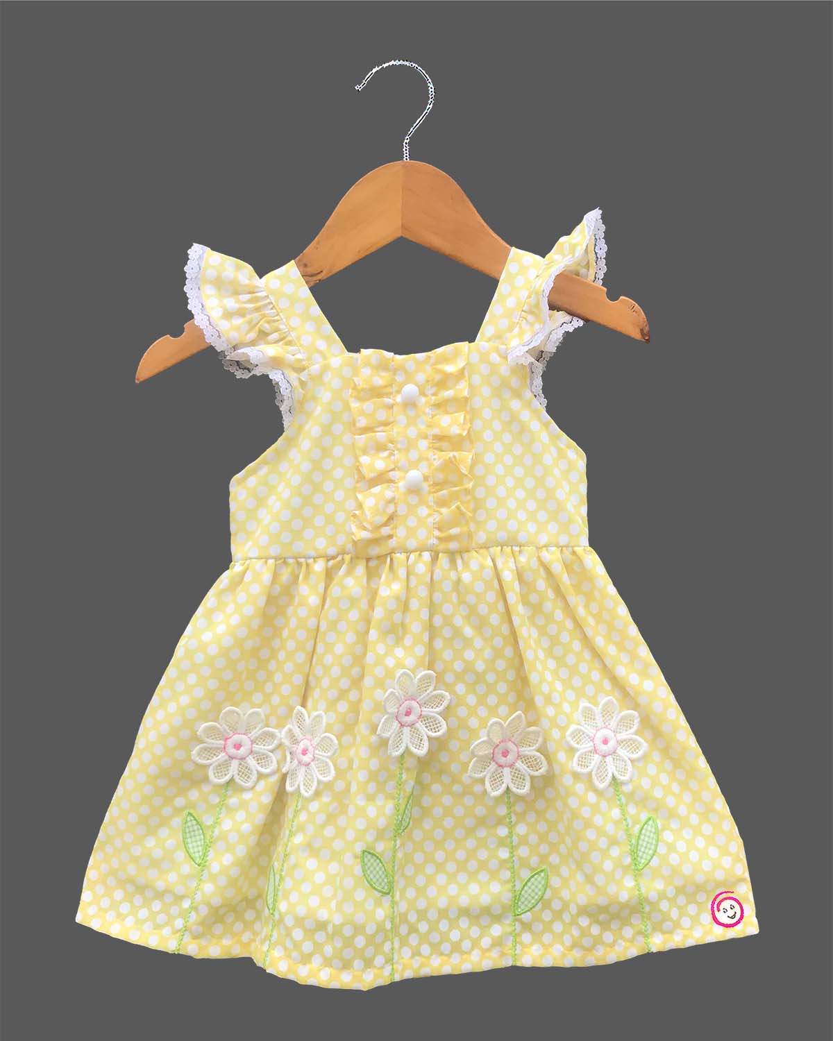 A charming casual dress for young girls featuring white polka dots and floral embroidery on a sunny background.