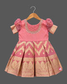 Girls pattu frock with organza puff sleeves, zari chevron box pleats and hand embroidered neckline on a hanger