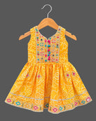 Sleeveless bandhani print short kurti with mirror work yoke paired with pattu langa for kids dhoti pants.