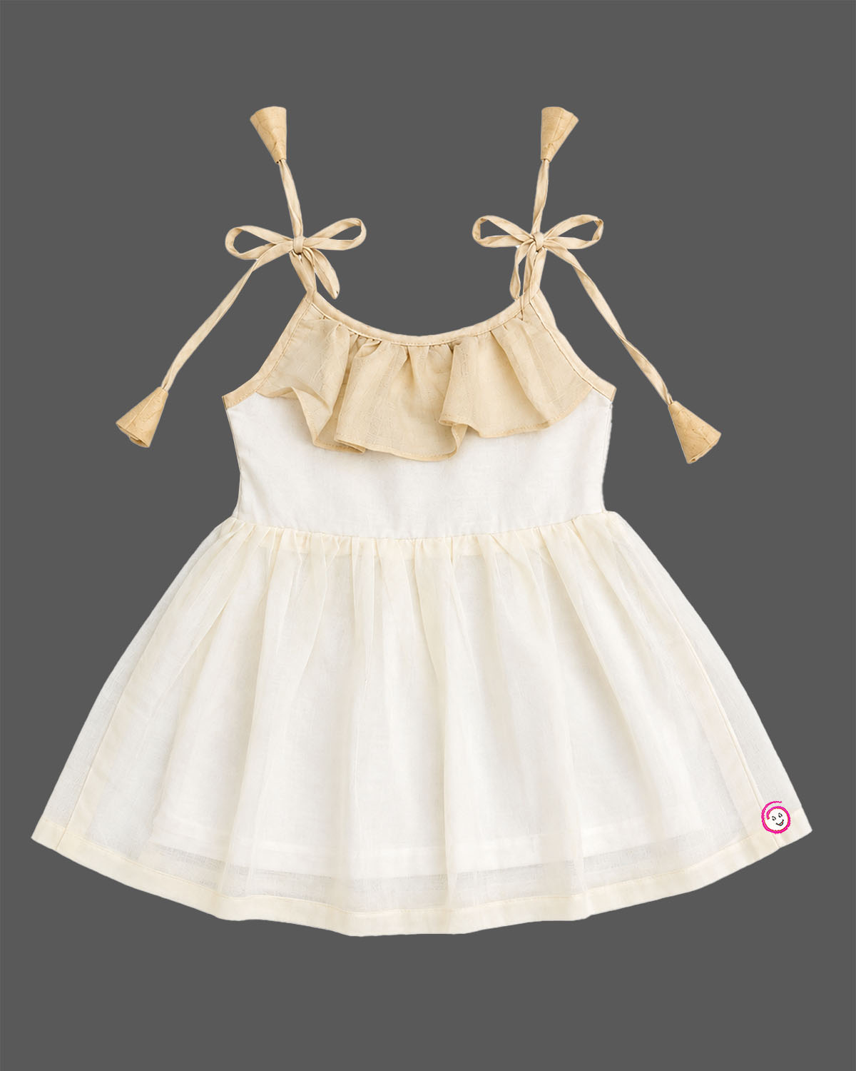 A sleeveless festival-inspired dress for children with ruffled detailing around the neck and decorative shoulder tie-ups ending in tassels.