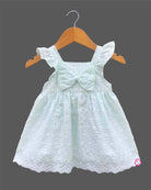Sleeveless toddler frock with dot embroidery, flutter shoulder straps, center chest bow, and scalloped lace hem.