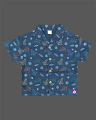 Young prince wearing space rocket patterned Cuban collar button shirt with matching elastic waistband shorts ensemble.