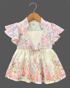 Elegant floral printed baby girl frock with layered flutter sleeves, a front knot accent, and a textured flared skirt displayed on a wooden hanger.