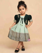 Infant  cotton silk frock in pastel mint green and dark bottle green with attached jacket style design, leaf embroidery, front tie-up tassels, and a traditional gold zari border