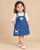 Baby party wear dress featuring a denim pinafore with bow embellishments and ribbed inner top for toddlers.