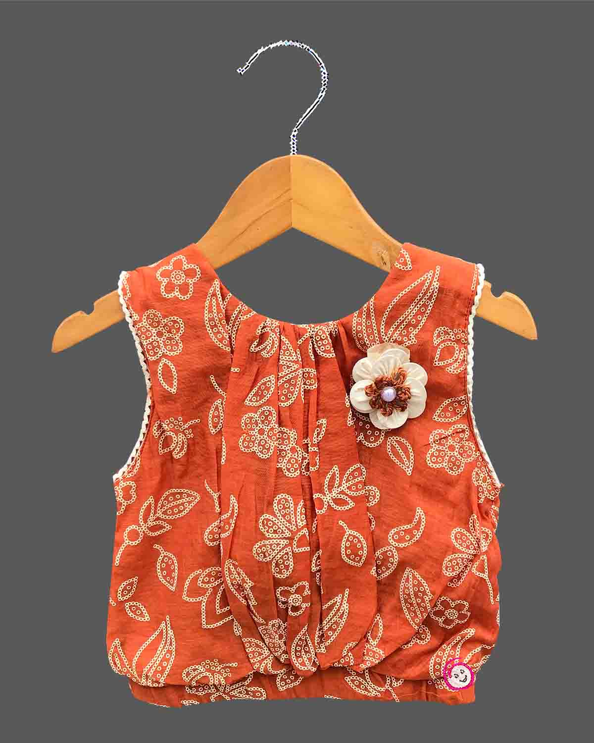 Sleeveless printed blouse adorned with a floral brooch paired with a box-pleated skirt for young girls