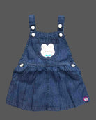 Toddler girl outfit set featuring textured puff sleeve blouse and denim pinafore dress with bunny patch detail and pleated skirt