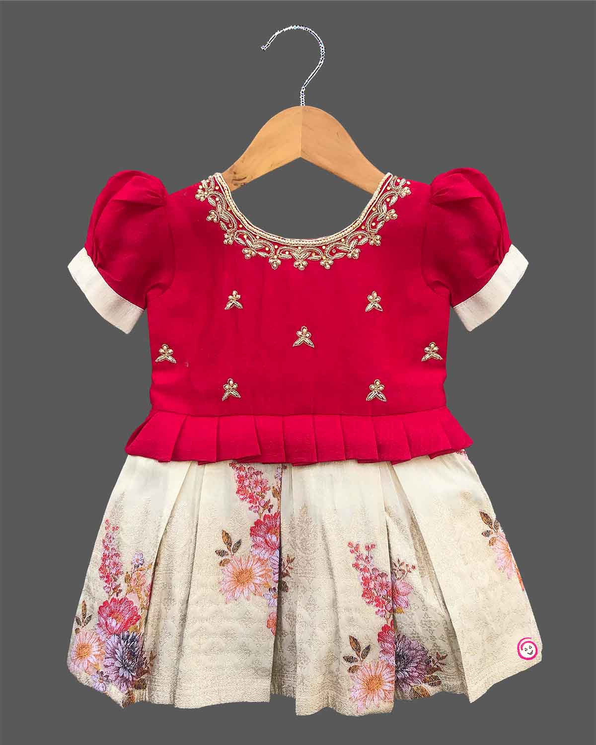 Detailed view of a kid's festive outfit with puff sleeves, intricate neck embroidery, and a pleated floral brocade skirt.