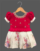 Detailed view of a kid's festive outfit with puff sleeves, intricate neck embroidery, and a pleated floral brocade skirt.