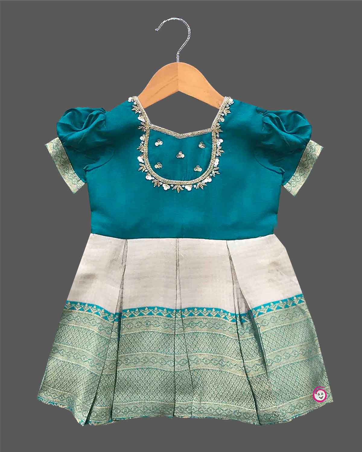 Infant silk festive frock featuring handcrafted neckline embroidery and zari woven hemline