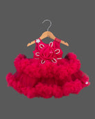 Voluminous party frock for little princess featuring a large statement rosette bodice and heavily ruffled tiered net skirt displayed on a hanger.
