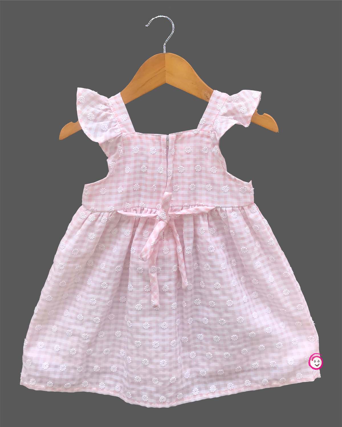 Sleeveless cotton casual frock with a checkered pattern and front bow detail hanging on a hanger.