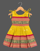 Toddler ethnic frock with jacquard woven borders, shoulder ties, and box pleats.