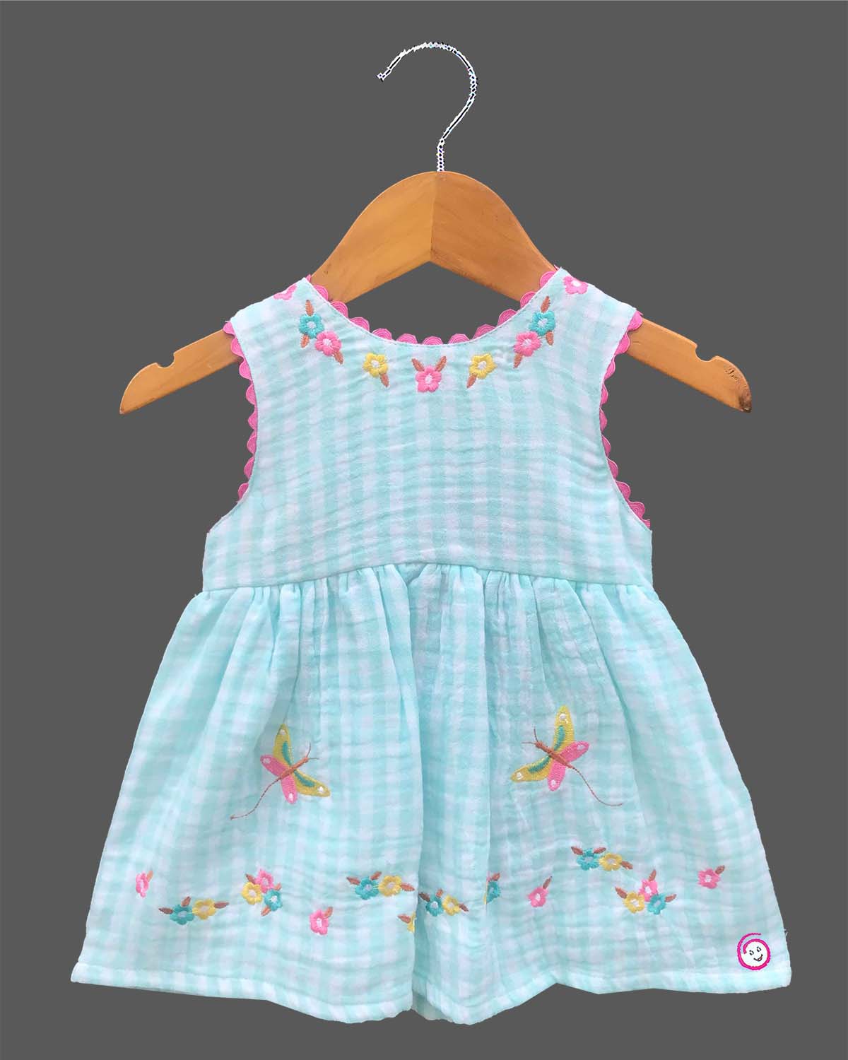 Sleeveless gingham cotton tunic dress for young girls featuring floral and butterfly embroidery with scalloped lace trim.