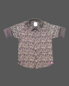 Front view of a printed collared shirt for boys with rolled-up cuffs and button closures on a neutral background.