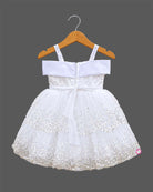 Girls sequined net frock with pearl embellished straps, satin bow with flower, and tiered scalloped flare skirt.