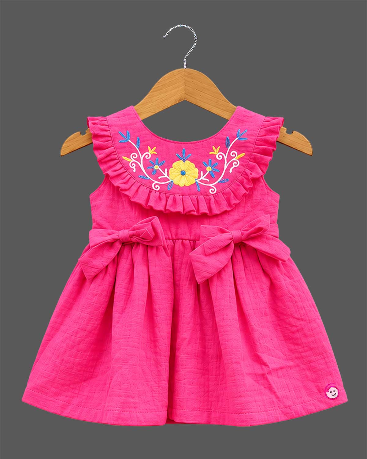 Toddler girls embroidered A-line frock with ruffled neckline, waist bow accents, and sleeveless cut.