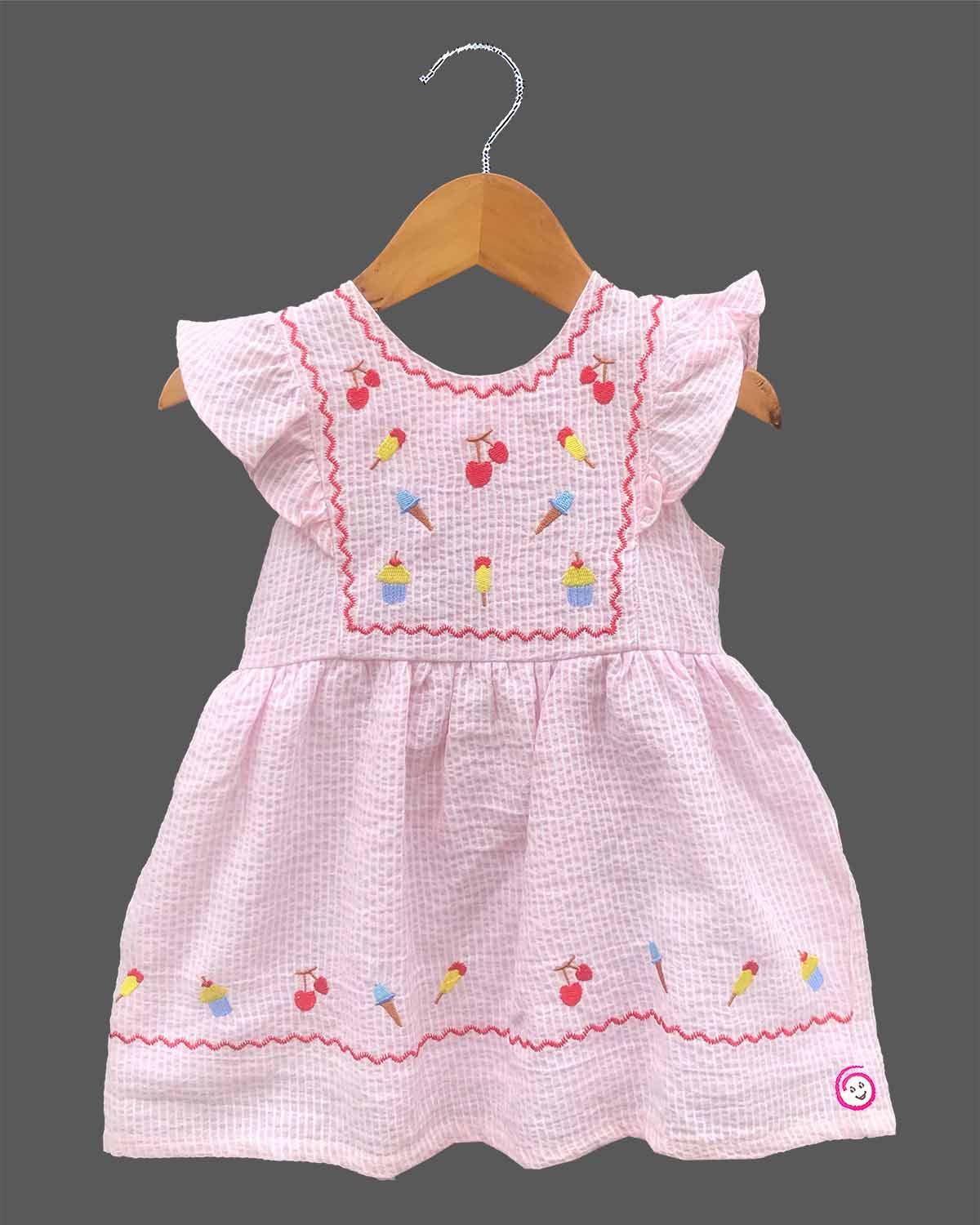 Close-up view of textured striped seersucker cotton fabric of a casual woven frock for young girls with brand product tag.