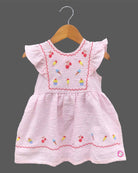 Close-up view of textured striped seersucker cotton fabric of a casual woven frock for young girls with brand product tag.