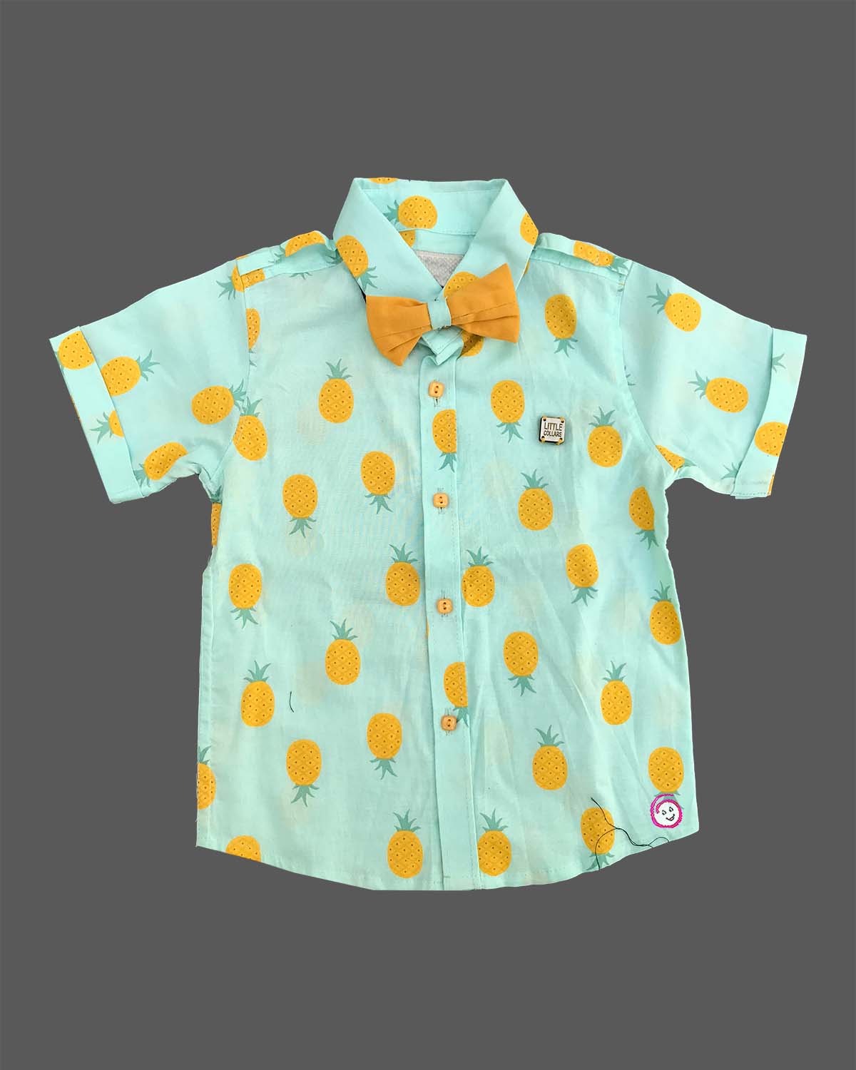 Boys attire featuring a tropical pattern button-down shirt, cargo style shorts, matching neck bow, and adjustable floral motif suspenders.