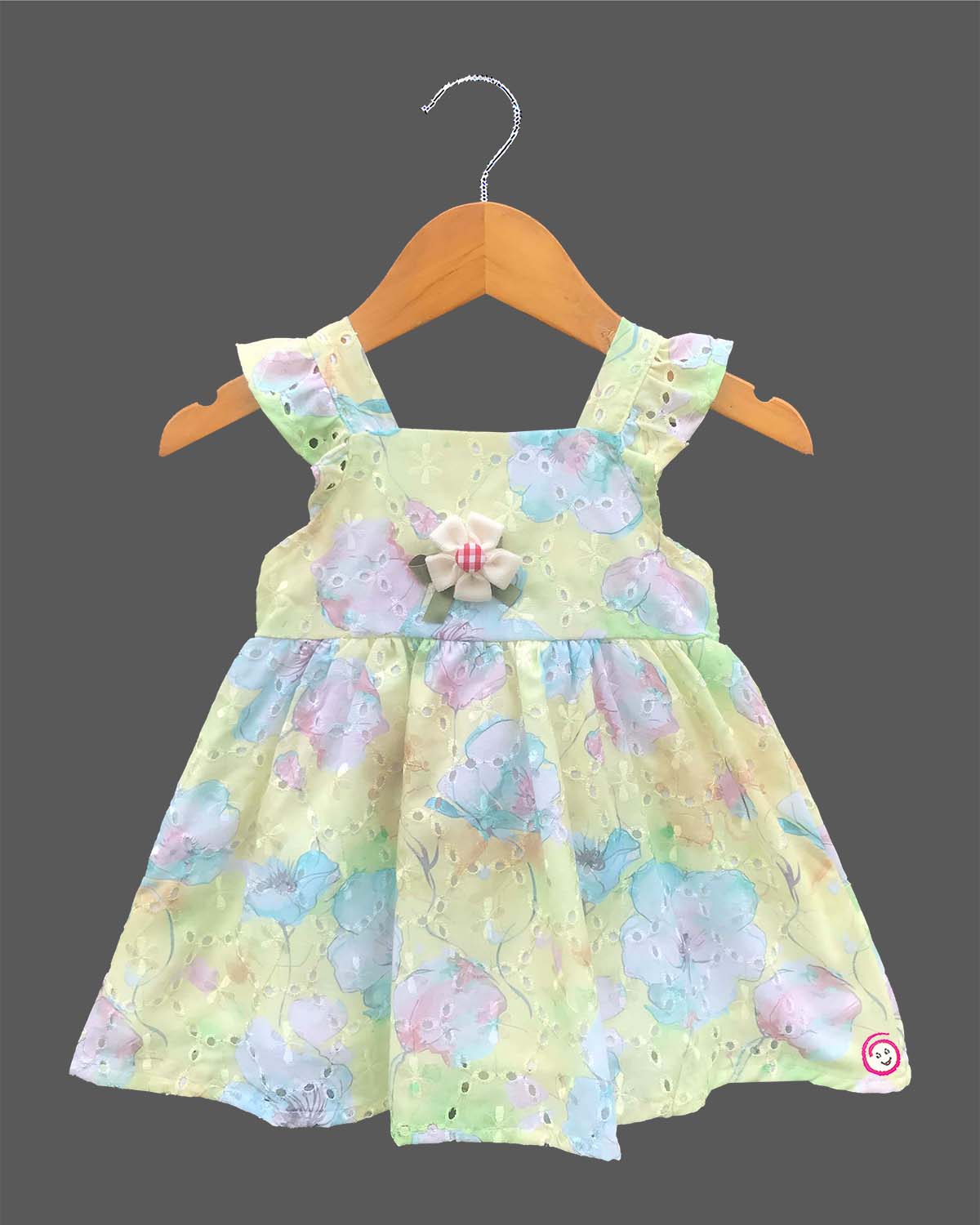 Sleeveless floral printed Schiffli cotton dress for toddlers with ruffled shoulder straps and a chest bow detail.