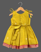 Toddler ethnic frock with jacquard woven borders, shoulder ties, and box pleats.