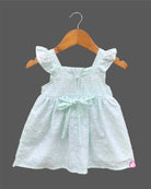 Sleeveless toddler frock with dot embroidery, flutter shoulder straps, center chest bow, and scalloped lace hem.