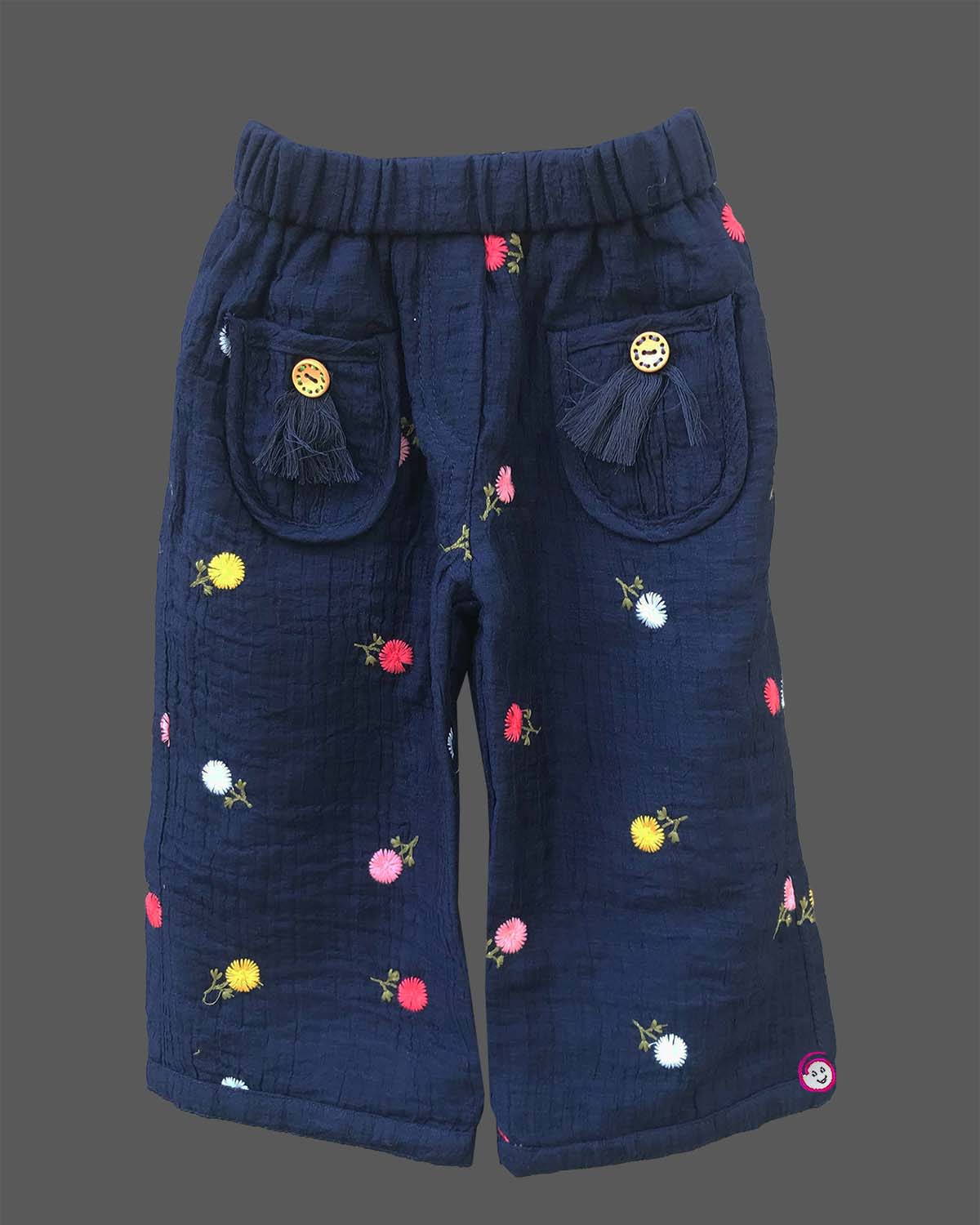Stylish two-piece set for baby girls featuring a collared short-sleeve top with contrast stitch trim and matching embroidered pants with tassel details on a hanger.