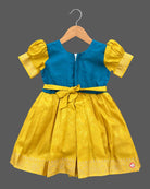 Girls silk cotton frock with embroidered round neckline, short puff sleeves, and floral jacquard pleated skirt.