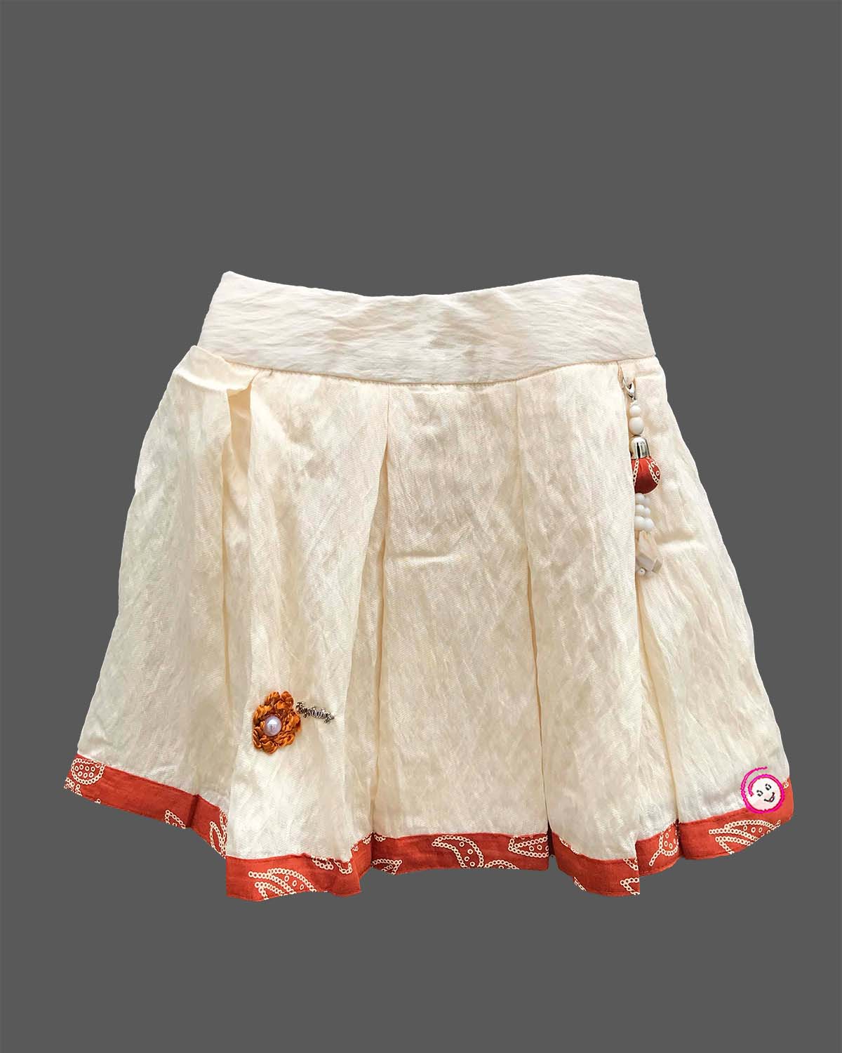 Sleeveless printed blouse adorned with a floral brooch paired with a box-pleated skirt for young girls