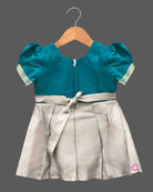 Infant silk festive frock featuring handcrafted neckline embroidery and zari woven hemline