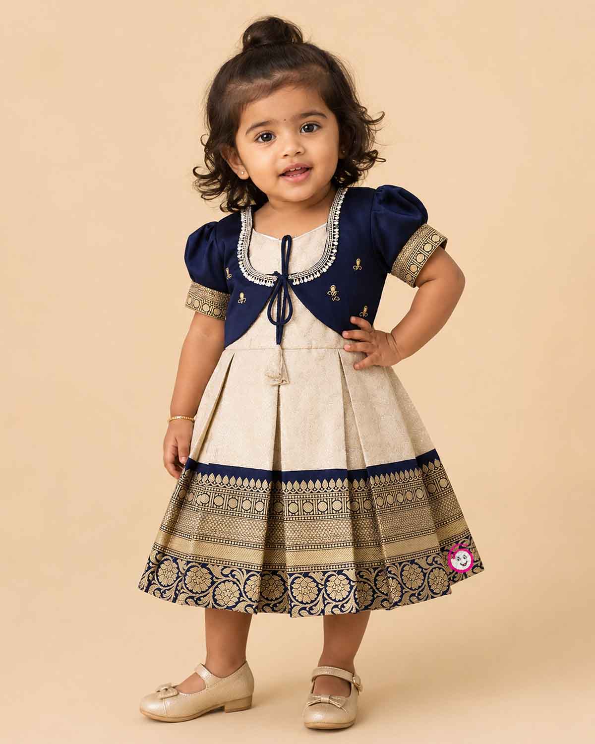 Infant silk cotton frock in cream and navy blue with attached jacket style design, front tie-up tassels, and a traditional heavy gold zari border