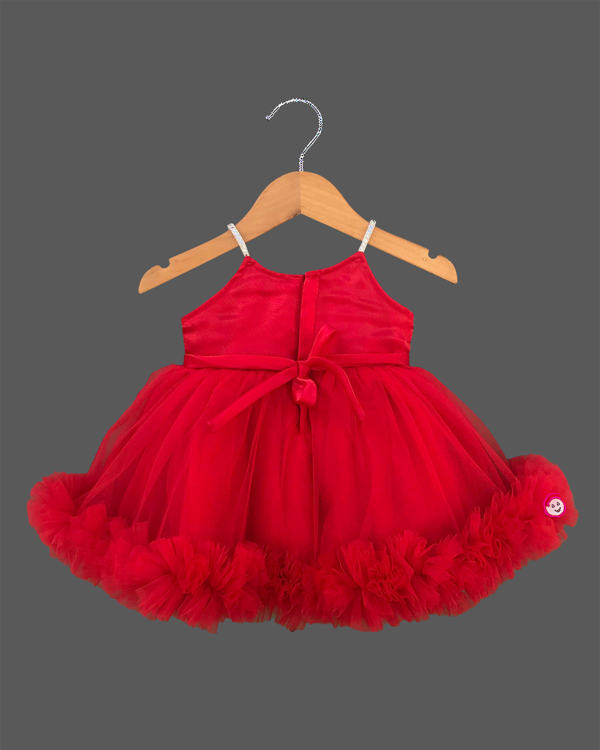 Elegant party frock for little princess with a grand 3D rose chest piece, sparkling spaghetti straps, and a dense ruffled net hemline hung on a wooden hanger.